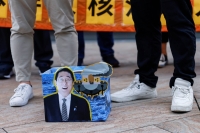 Protesters in Hong Kong stand near a cardboard sign featuring Japanese Prime Minister Fumio Kishida on Friday during a demonstration after Tokyo began releasing treated radioactive water from the crippled Fukushima No. 1 nuclear plant into the sea. | REUTERS