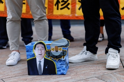 Protesters in Hong Kong stand near a cardboard sign featuring Japanese Prime Minister Fumio Kishida on Friday during a demonstration after Tokyo began releasing treated radioactive water from the crippled Fukushima No. 1 nuclear plant into the sea.