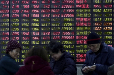 Investors stand in front of an electronic board showing stock information on the first trading day after the weeklong Lunar New Year holiday at a brokerage house in Shanghai.