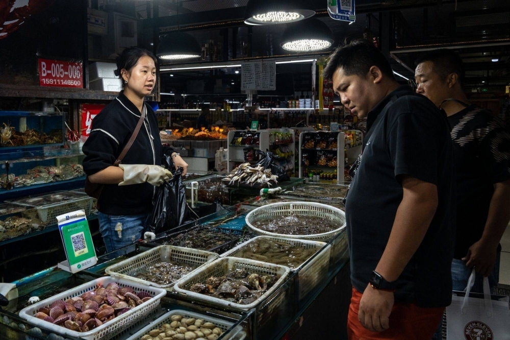 Customers shop at a seafood market in Beijing on Friday.