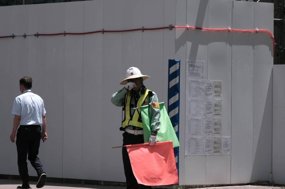 A worker directing traffic in front of a construction site in the city of Fukushima on July 6.