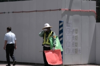 A worker directing traffic in front of a construction site in the city of Fukushima on July 6. | Bloomberg
