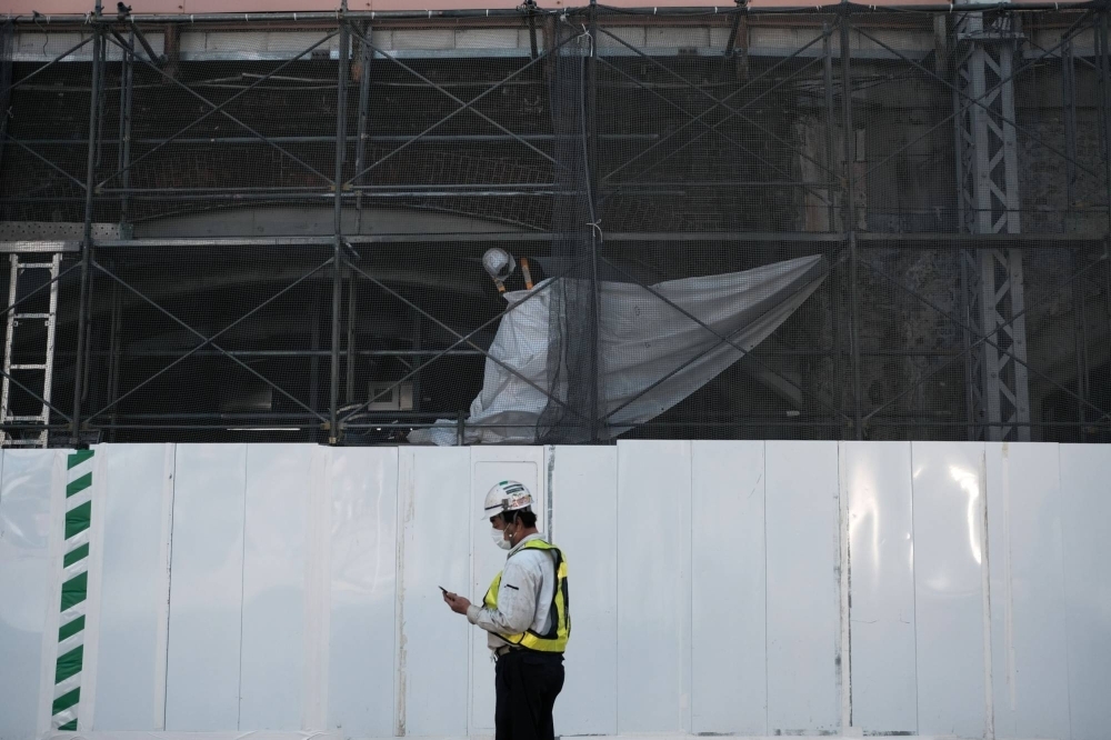 A worker looks at a smartphone in front of a construction site in the Shimbashi district in Tokyo in May 2020.