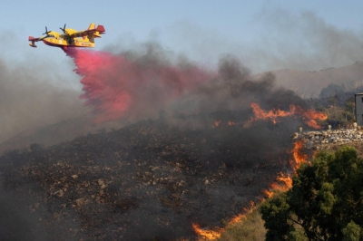 An aircraft drops flame retardant on burning vegetation in Sicily, Italy, on Sunday.