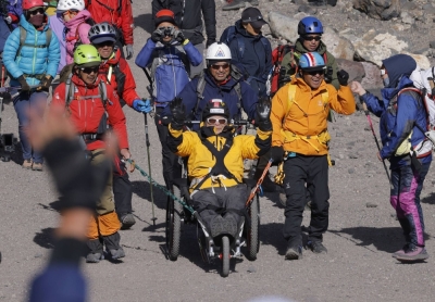 Alpinist Yuichiro Miura, seated on an all-terrain wheelchair, waves after reaching the summit of Mount Fuji on Thursday.