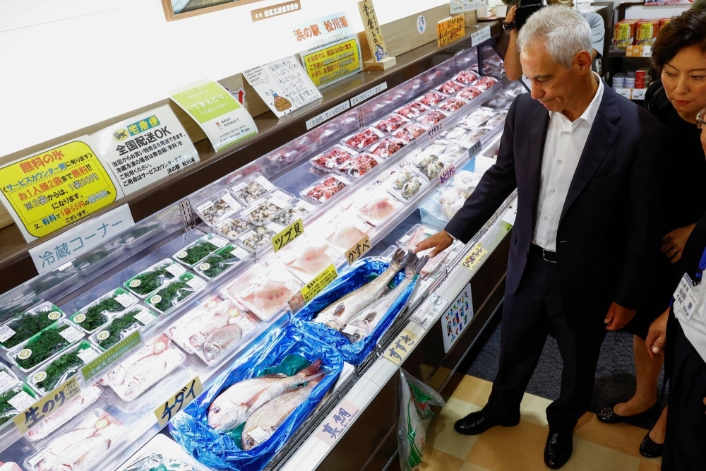 U.S. Ambassador to Japan Rahm Emanuel looks at locally caught fish at the Hamanoeki Fish Market during his visit to Soma, Fukushima Prefecture, on Thursday.