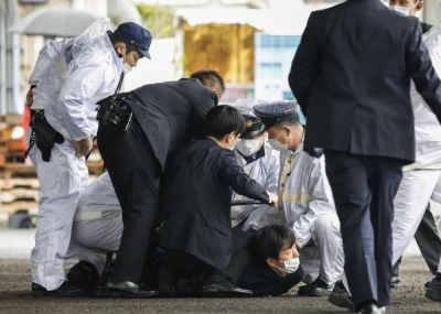 Ryuji Kimura is subdued after allegedly throwing a pipe bomb at Prime Minister Fumio Kishida before he was due to make a stump speech at a fishing port in the city of Wakayama on April 15.