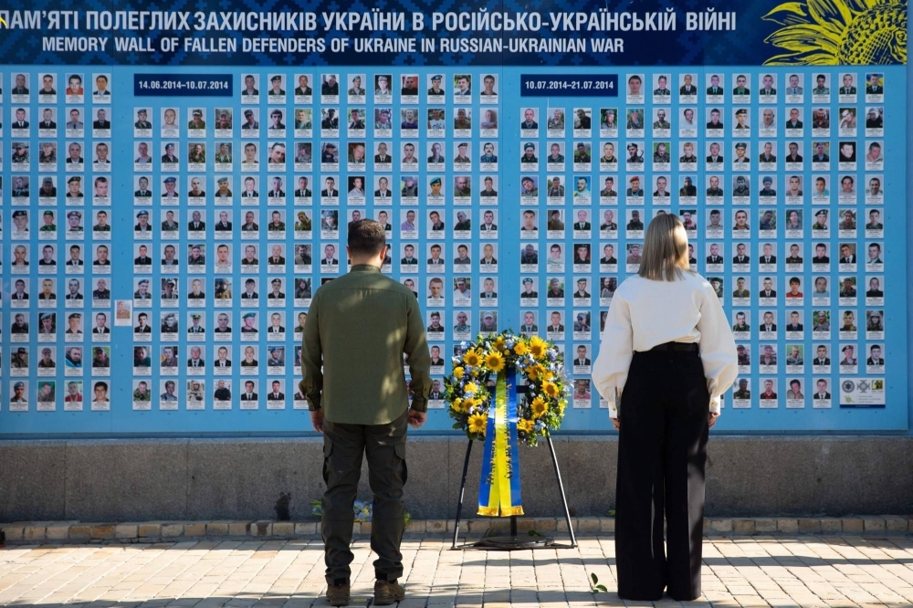 Ukrainian President Volodymyr Zelenskyy and his wife, Olena Zelenska, attend a wreath-laying ceremony at a memorial wall outside of Orthodox Saint Michael's Golden-Domed Monastery during Ukraine's Independence Day celebrations in Kyiv on Aug. 24. 