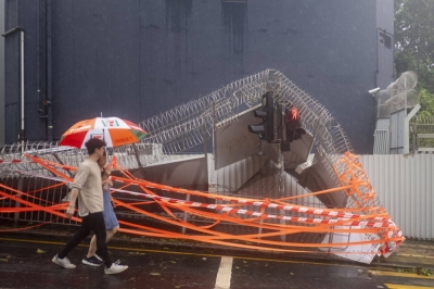People walk past a damaged wall at the West Kowloon Regional Police Headquarters following Typhoon Saola in Hong Kong on Saturday.