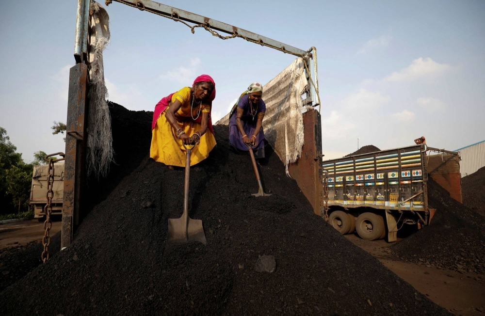 Workers unload coal from a supply truck at a yard on the outskirts of Ahmedabad, India.