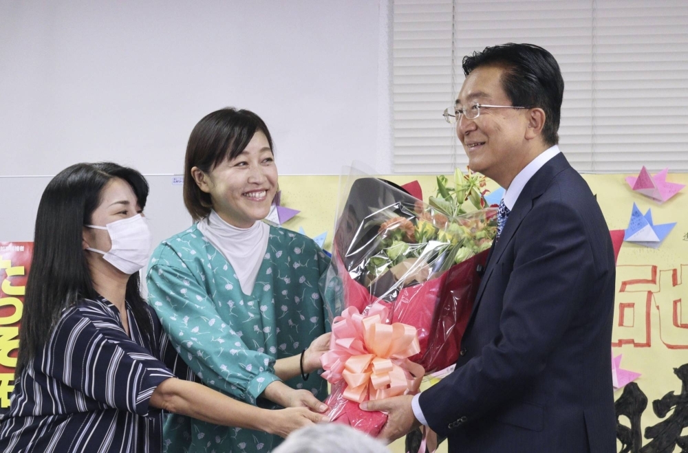 Iwate Gov. Takuya Tasso (right) receives flowers in Morioka, Iwate Prefecture, on Sunday after winning a fifth term as governor.