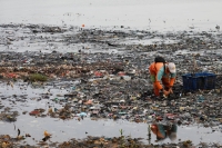 A municipality worker collects garbage, most of which is plastic and domestic waste, along the shore of Jakarta. | REUTERS
