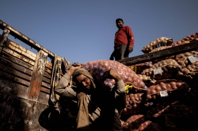 Workers unload sacks of onions from a truck at a wholesale market in Ghaziabad, Uttar Pradesh, India, on April 5.