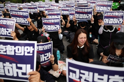 A South Korean teacher reacts as others chant slogans during a protest to demand better protection of their rights and to mourn a young teacher found dead in July in an apparent suicide, in Seoul on Monday. The signs read "Vote for an agreement on the protection of teachers' rights."