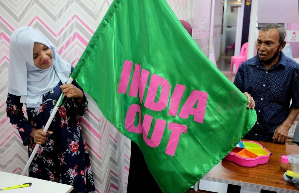 A Progressive Party of Maldives worker poses with an "India Out" flag in Male, Maldives, in March 2022.