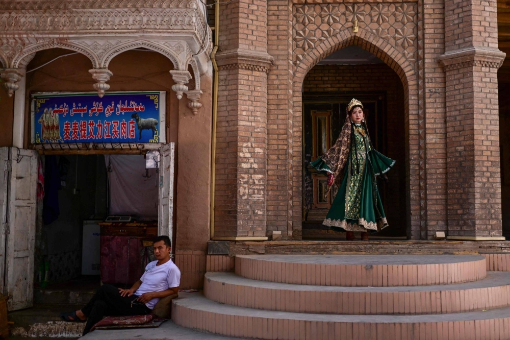 A woman wears traditional Uyghur clothing for a photo shoot in the Old Kashgar tourist area in China's northwestern Xinjiang region.