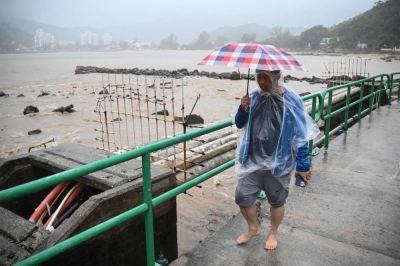 A man walks on a bridge over a swollen river on Lantau Island in Hong Kong on Friday.