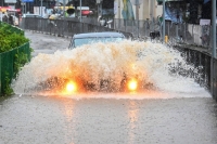 A car drives through floodwaters on Lantau Island in Hong Kong on Friday. | AFP-Jiji