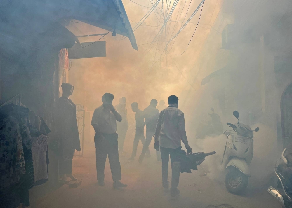 A health worker in New Delhi fumigates an alley in a residential neighborhood to prevent the spread of mosquito-borne diseases.