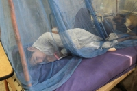 A dengue fever patient lies under a mosquito net inside at Lady Reading Hospital in Peshawar, Pakistan. | REUTERS