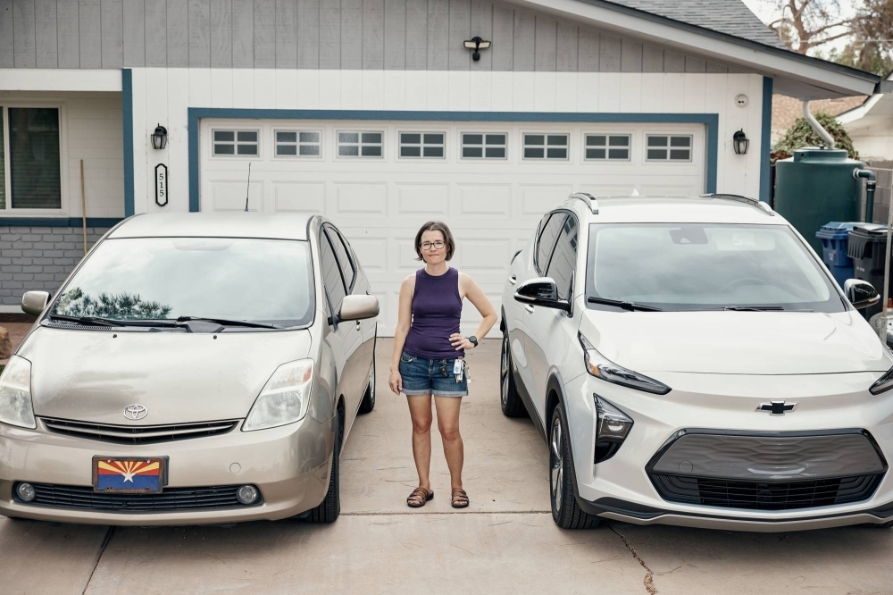 Rachel Culin, a disenchanted Toyota owner, standing between her Toyota Prius and new Chevy Bolt at her home in Mesa, Arizona. The world’s largest carmaker dominates the sales of hybrid cars but has been slow to sell all-electric vehicles, alienating some customers and hurting sales.