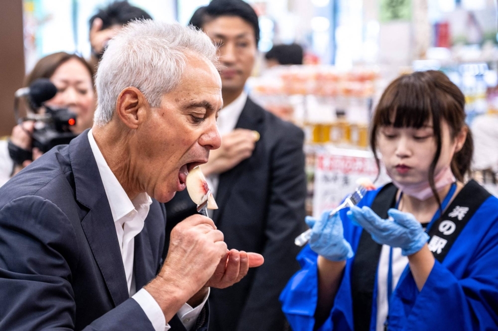 U.S. Ambassador to Japan Rahm Emanuel eats a peach as he visits Hamanoeki Fish Market and Food Court, as part of his trip to Soma, Fukushima Prefecture, on Aug. 31.