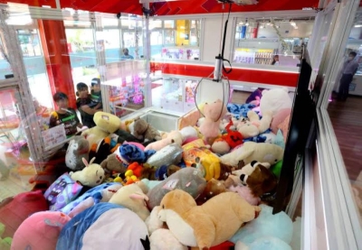 A family plays the Monster Catcher crane game at Happy Land Marina amusement arcade in Hiroshima.