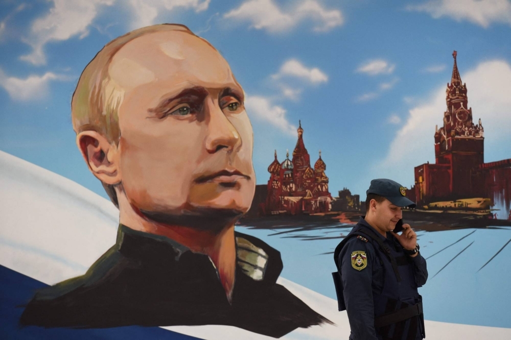 A Russian rescuer speaks on his mobile phone next to a wall bearing an image of Russian President Vladimir Putin, at a polling station during local elections organized by the Russian-installed authorities in Donetsk, Russian-controlled Ukraine, on Friday.