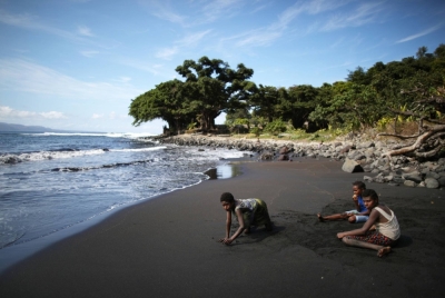 Young villagers gather on the black sand beach in the village of Waisisi in Tanna, Vanuatu.