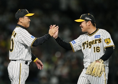 Tigers pitcher Yuki Nishi (right) celebrates with manager Akinobu Okada after throwing a shutout against the Giants at Koshien Stadium in Nishinomiya, Hyogo Prefecture, on Tuesday.