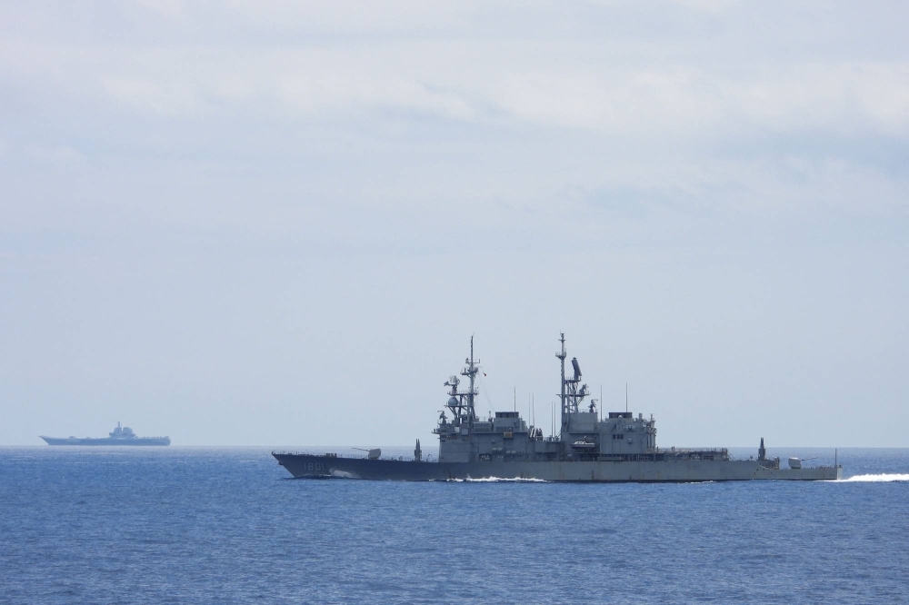 Chinese aircraft carrier Shandong (left) while being monitored by a Taiwanese Keelung class warship (right) at sea. Taiwan said on Wednesday that it had detected numerous Chinese warplanes around the island.