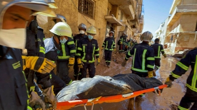 Members of rescue teams from the Egyptian army carry a body as they walk through mud between buildings destroyed by flooding in Derna, Libya, on Wednesday.