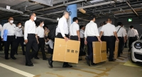 Police investigators head to Bigomotor's headquarters on the 20th floor of the Roppongi Hills complex in Tokyo's Minato Ward from an underground parking on Friday. | Kyodo