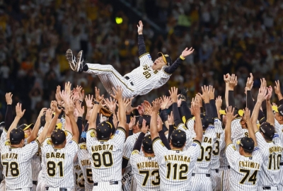 The Tigers toss manager Akinobu Okada into the air as they celebrate after winning the Central League pennant on Thursday at Koshien Stadium in Nishinomiya, Hyogo Prefecture.