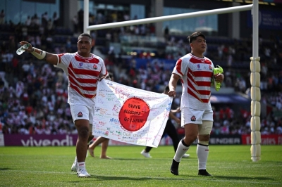 Japan's Asaeli Ai Valu (left) and Atsushi Sakate celebrate with a Japanese flag after defeating Chile in their opening game of the Rugby World Cup in Toulouse, France, on Sept. 10.