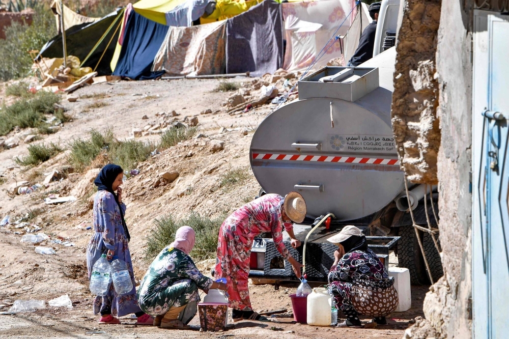 Survivors fill up water from a tanker truck in the earthquake-hit village of Ineghede in Morocco on Sunday.