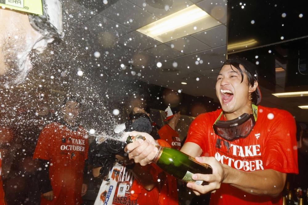 Shintaro Fujinami celebrates with his teammates after the Orioles clinched a spot in the MLB postseason on Sunday.