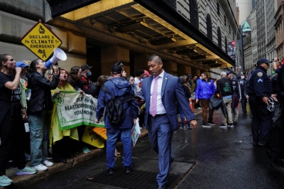A man in a business suit walks past activists during Climate Week in the Financial District of New York on Monday.