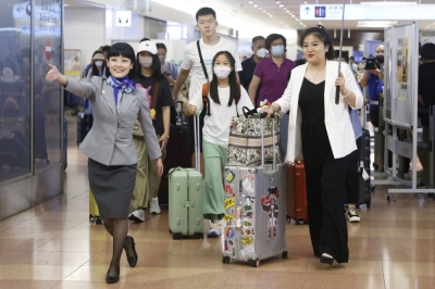 An All Nippon Airways employee (left) escorts a group of Chinese tourists and a tour conductor (right) at the arrival lobby of Haneda Airport in Tokyo in August.