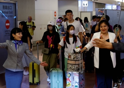 An All Nippon Airways worker and a travel agency representative escort members of a Chinese tour group from Beijing upon their arrival at Haneda Airport in Tokyo on Aug. 23.