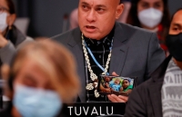 Tuvalu's Finance Minister Seve Paeniu shows a picture of his grandchildren on his phone while attending the U.N. Climate Change Conference in Glasgow in November 2021. | REUTERS