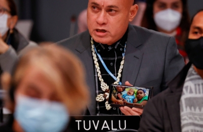 Tuvalu's Finance Minister Seve Paeniu shows a picture of his grandchildren on his phone while attending the U.N. Climate Change Conference in Glasgow in November 2021.