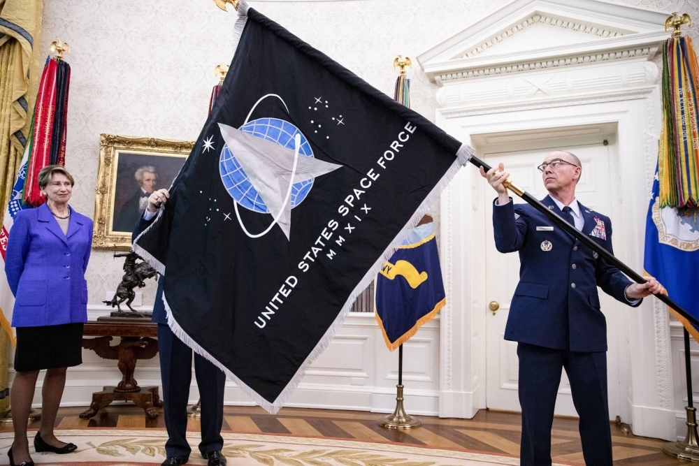 The official U.S. Space Force flag is held during a presentation in the Oval Office of the White House in Washington in May 2020. 