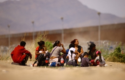 Migrants from Venezuela, seeking asylum in the United States, sit before crossing the Rio Bravo river with the intention of turning themselves in to the U.S. Border Patrol agents, as seen from Ciudad Juarez, Mexico, on Thursday.