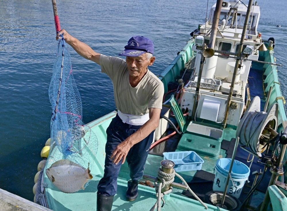 A fisherman unloads a flounder at Matsukawaura Fishing Port in the city of Soma, Fukushima Prefecture, on Aug. 31. Japan's fishery industry has taken a big hit since the country started releasing treated water from the Fukushima No. 1 nuclear power plant after the Chinese government imposed a blanket ban on Japanese seafood imports.
