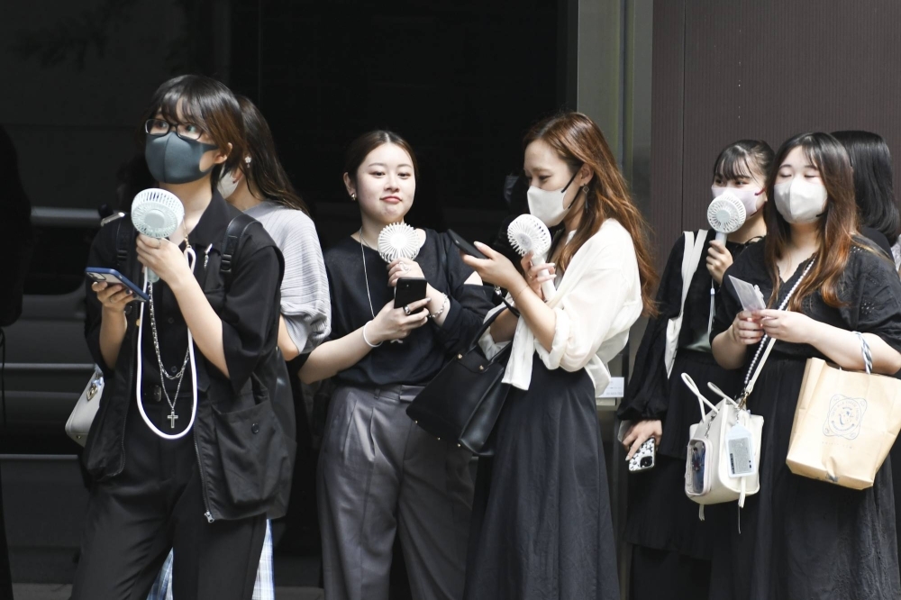 Women with portable electric fans in the Yurakucho district of Tokyo on Sept. 12. In Japan, Cool Biz became especially popular with women, who tended to wear lighter clothes and often complained about the cold temperatures needed to make business suits comfortable for their male colleagues.