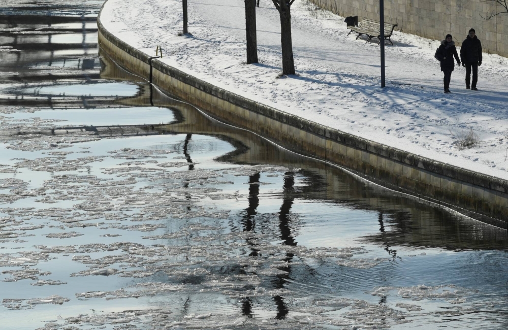 People walk on the bank of the frozen Spree river in Berlin in 2021.