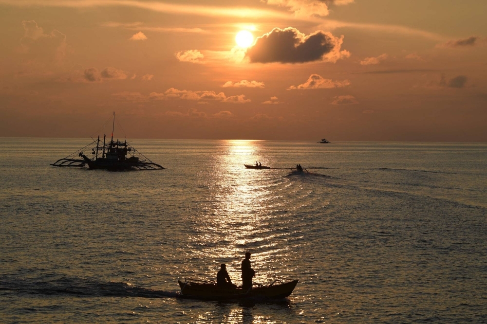 Philippine fishermen catch fish as the sun rises near the Chinese-controlled Scarborough Shoal in the disputed South China Sea on Sept. 21.