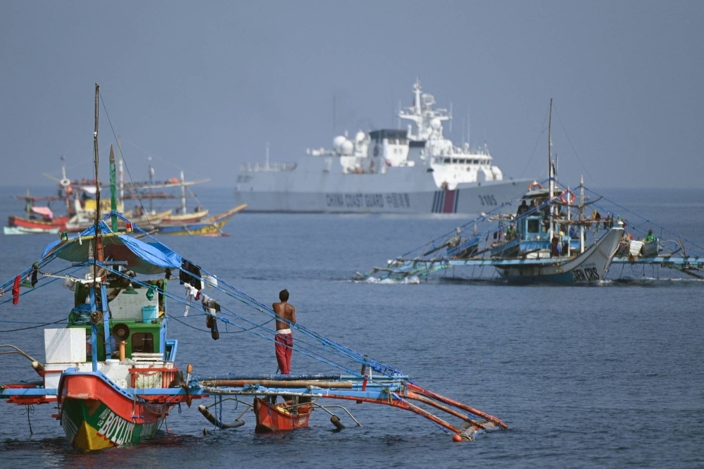 A Chinese coast guard vessel (rear center) shadows Philippine fishing boats anchored near the Chinese-controlled Scarborough Shoal in disputed waters of the South China Sea on Sept. 21. 