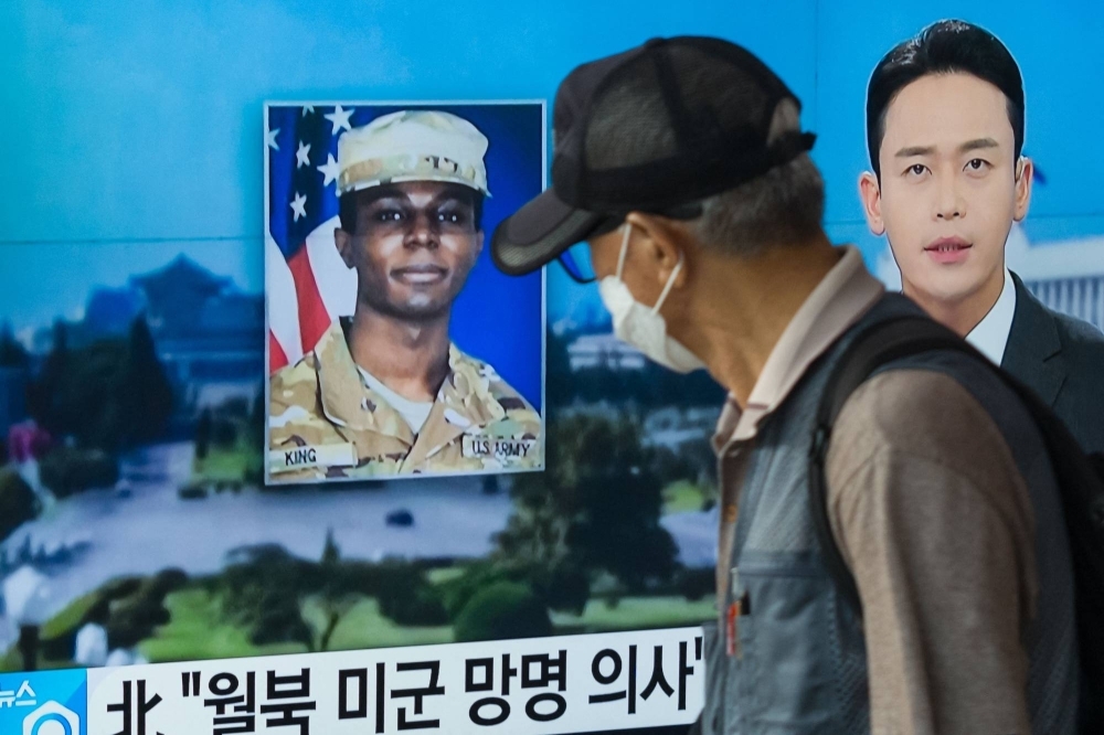 A man walks past a television showing a news broadcast featuring a photo of U.S. soldier Travis King, who ran across the border into North Korea while part of a tour group visiting the Demilitarized Zone on South Korea's border, in Seoul, on Aug. 16.